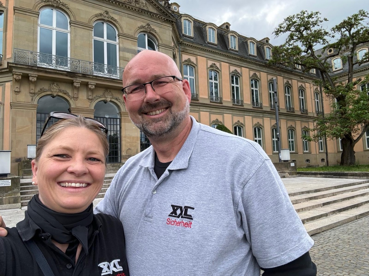 Katrin und Carsten lächeln gemeinsam in ihrer XXL-Sicherheit-Kleidung.